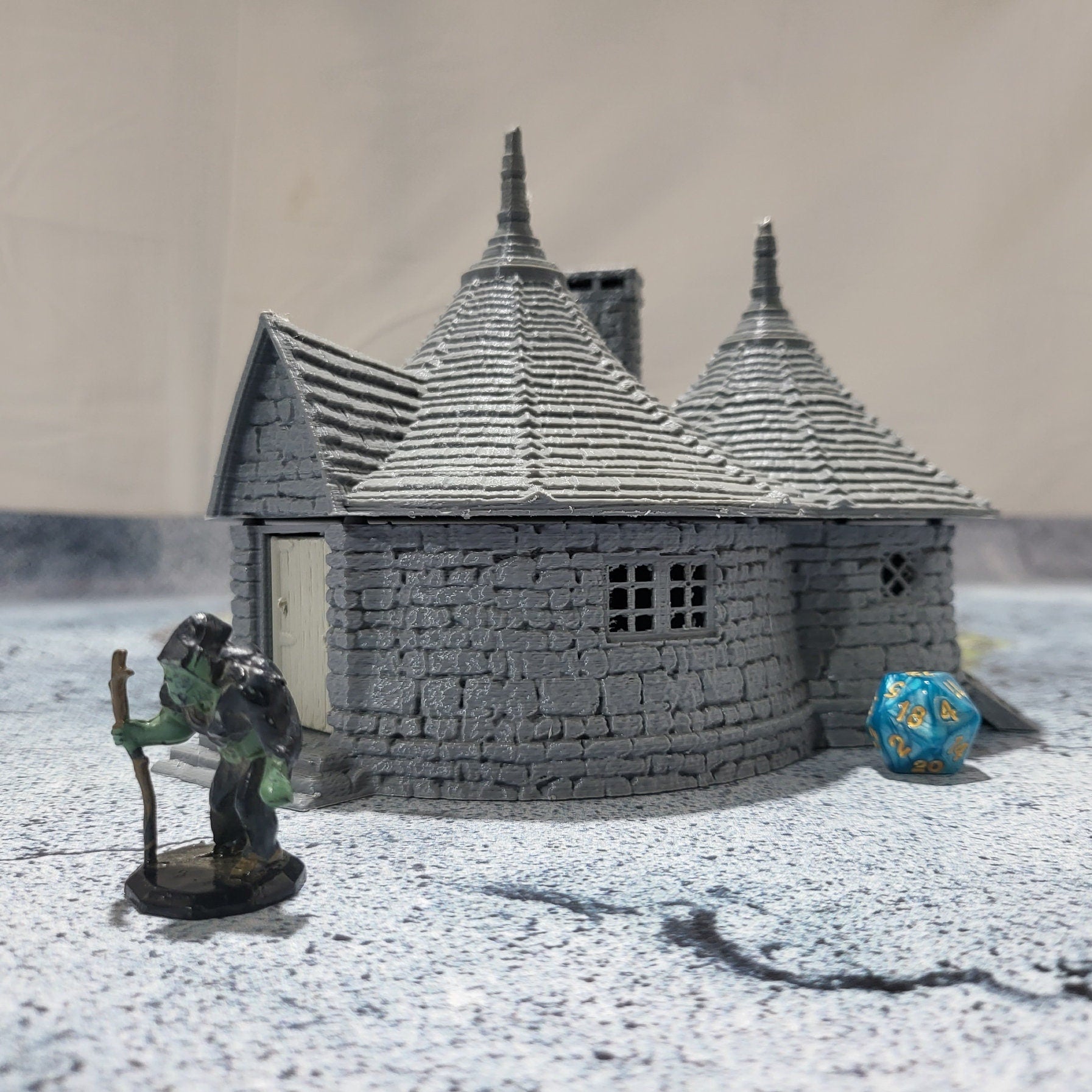 A highly detailed 3D-printed model of the Dragonspire Gamekeeper&#39;s Lodge, featuring two rooms, a fireplace with chimney, front and back doors, and a round roof design.