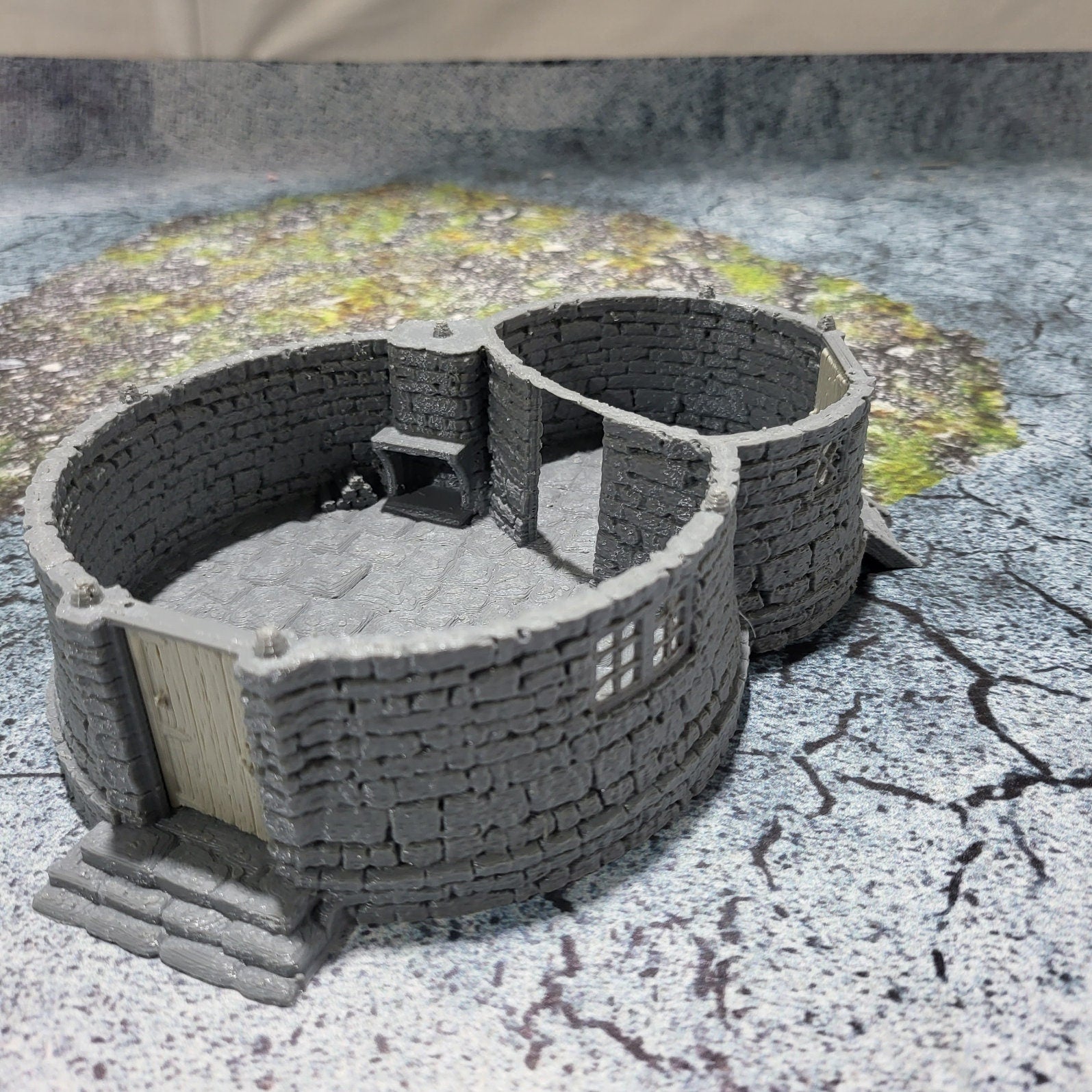 A highly detailed 3D-printed model of the Dragonspire Gamekeeper&#39;s Lodge, featuring two rooms, a fireplace with chimney, front and back doors, and a round roof design.