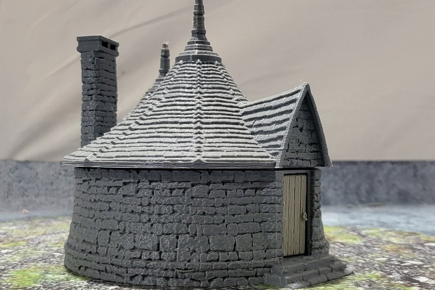 A highly detailed 3D-printed model of the Dragonspire Gamekeeper&#39;s Lodge, featuring two rooms, a fireplace with chimney, front and back doors, and a round roof design.