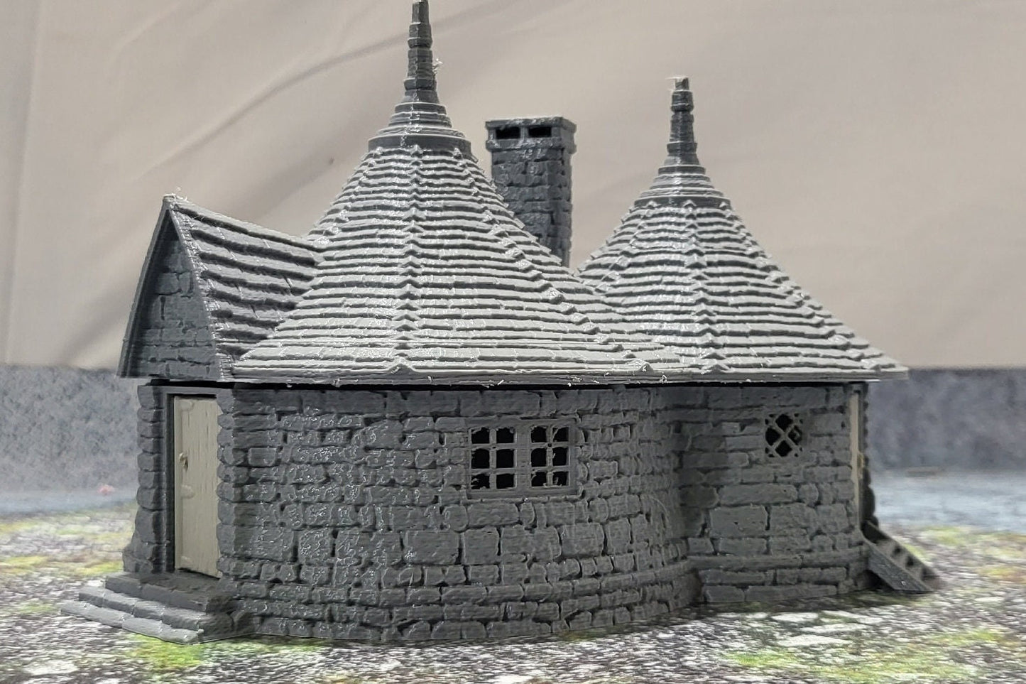 A highly detailed 3D-printed model of the Dragonspire Gamekeeper&#39;s Lodge, featuring two rooms, a fireplace with chimney, front and back doors, and a round roof design.