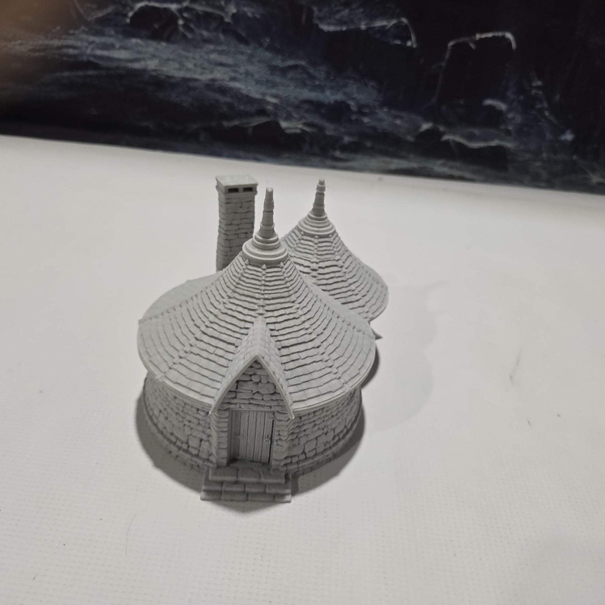 A highly detailed 3D-printed model of the Dragonspire Gamekeeper&#39;s Lodge, featuring two rooms, a fireplace with chimney, front and back doors, and a round roof design.