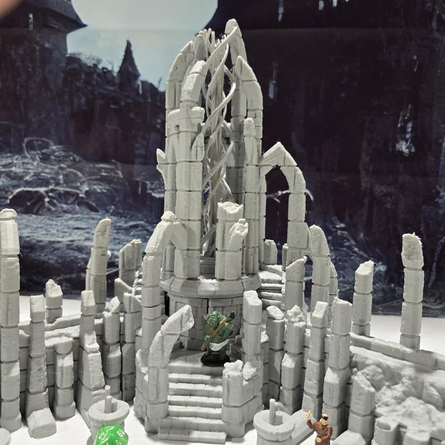 A detailed ruined elven altar featuring intricate carvings and statues, with a central spiral column and surrounding broken pillars. The scene includes multiple staircases and platforms, providing a mystical and ancient ambiance for tabletop games.