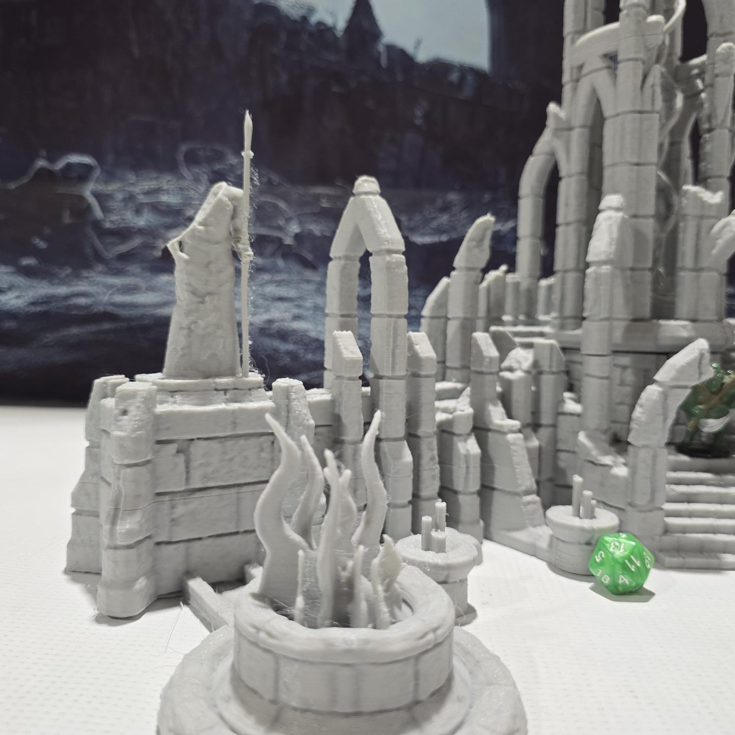 A detailed ruined elven altar featuring intricate carvings and statues, with a central spiral column and surrounding broken pillars. The scene includes multiple staircases and platforms, providing a mystical and ancient ambiance for tabletop games.