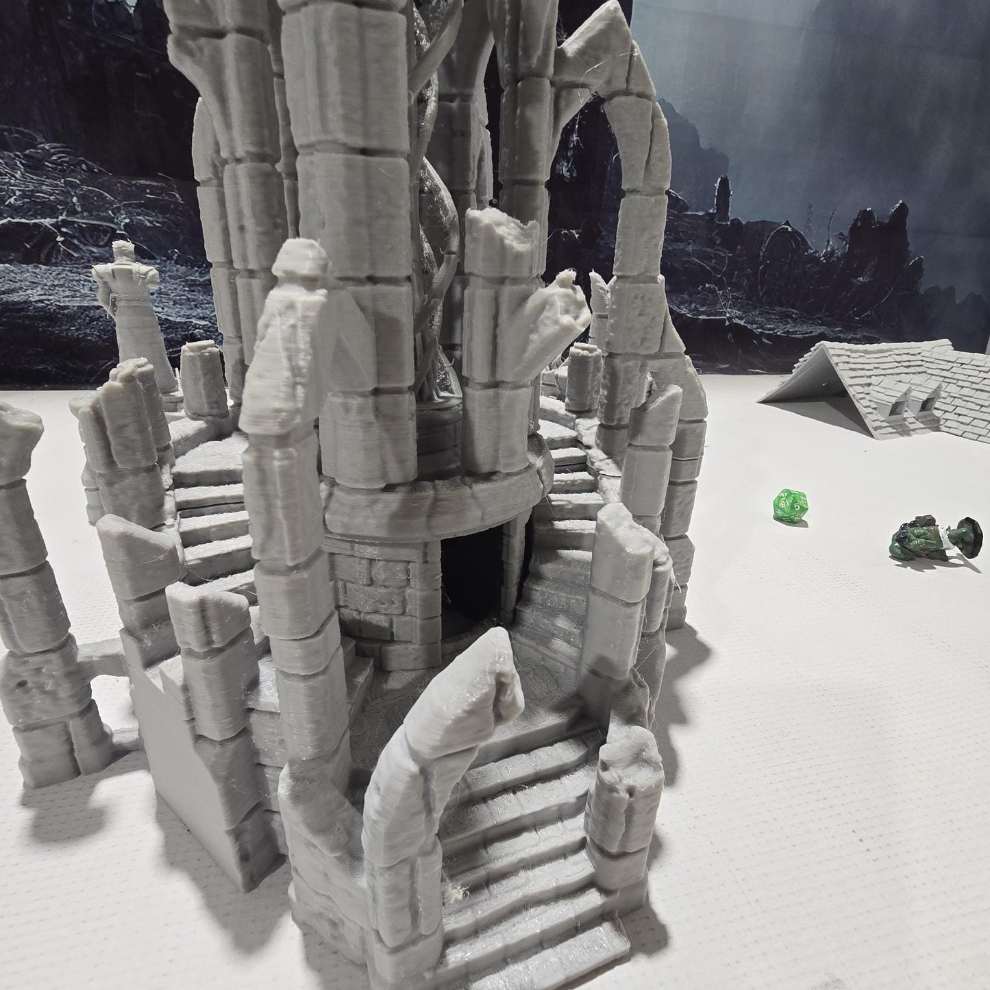 A detailed ruined elven altar featuring intricate carvings and statues, with a central spiral column and surrounding broken pillars. The scene includes multiple staircases and platforms, providing a mystical and ancient ambiance for tabletop games.