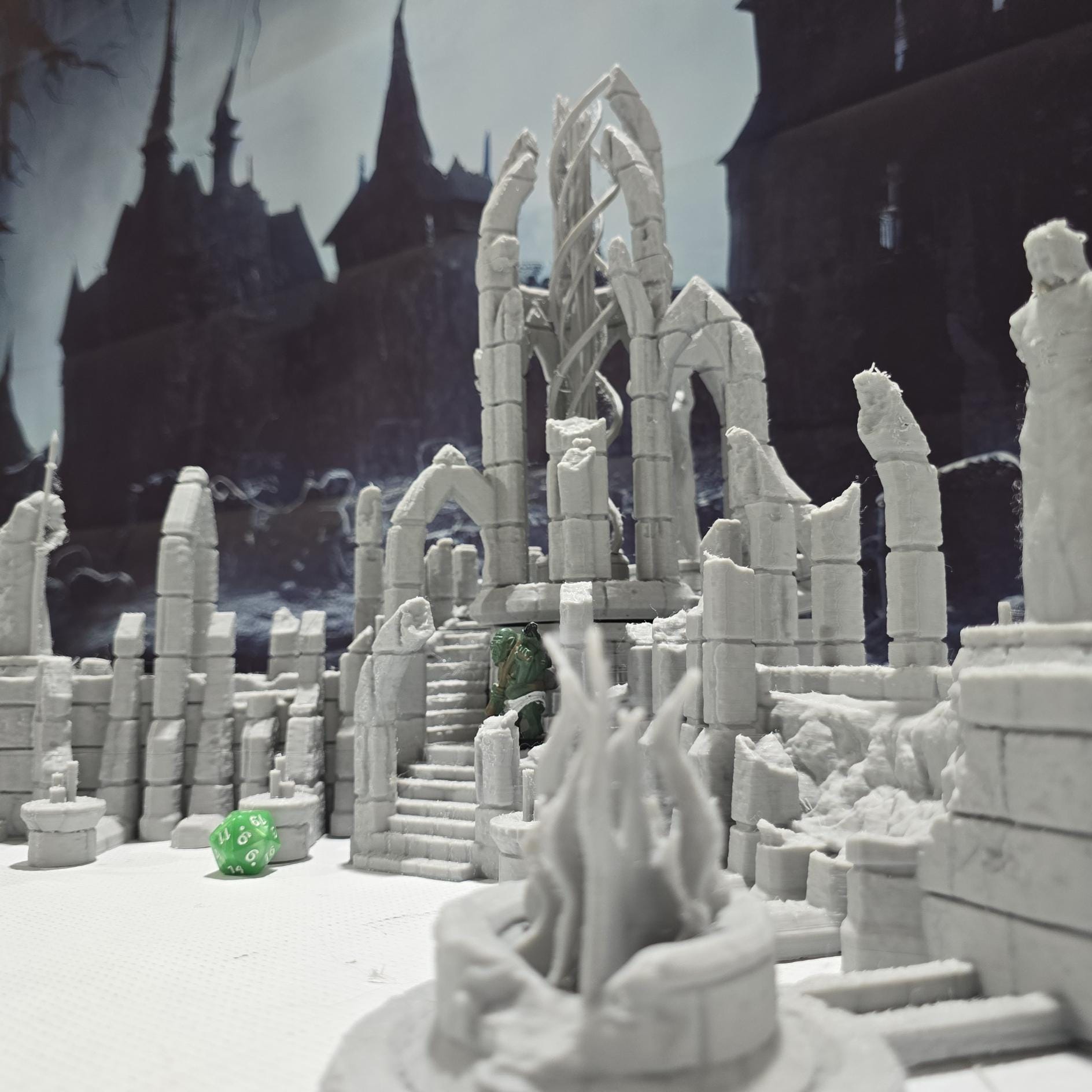 A detailed ruined elven altar featuring intricate carvings and statues, with a central spiral column and surrounding broken pillars. The scene includes multiple staircases and platforms, providing a mystical and ancient ambiance for tabletop games.