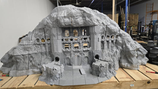 3D printed model of a Dwarf Mountain Stronghold, featuring towering stone structures, fortified walls, and intricate mountain carvings. The fortress includes multiple levels and archways, ideal for enhancing fantasy RPGs and wargaming scenarios.